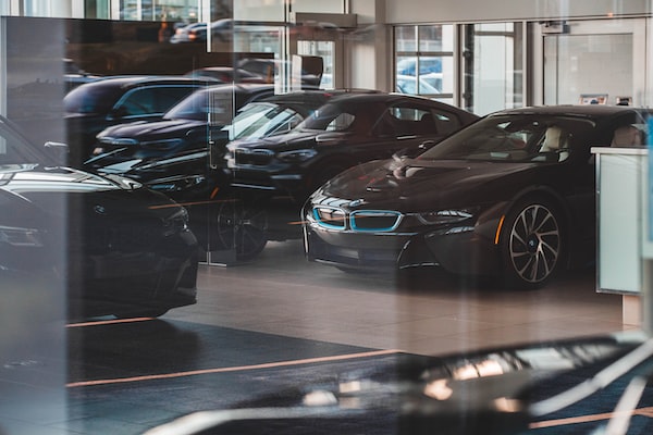 Interior of a showroom at a car dealership with a burgundy BMW and several other cars